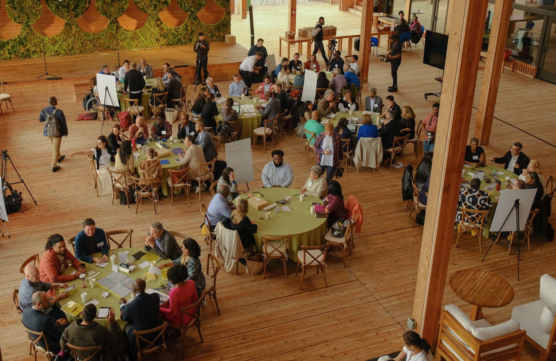 Overhead view of a full room of round tables under a timber roof