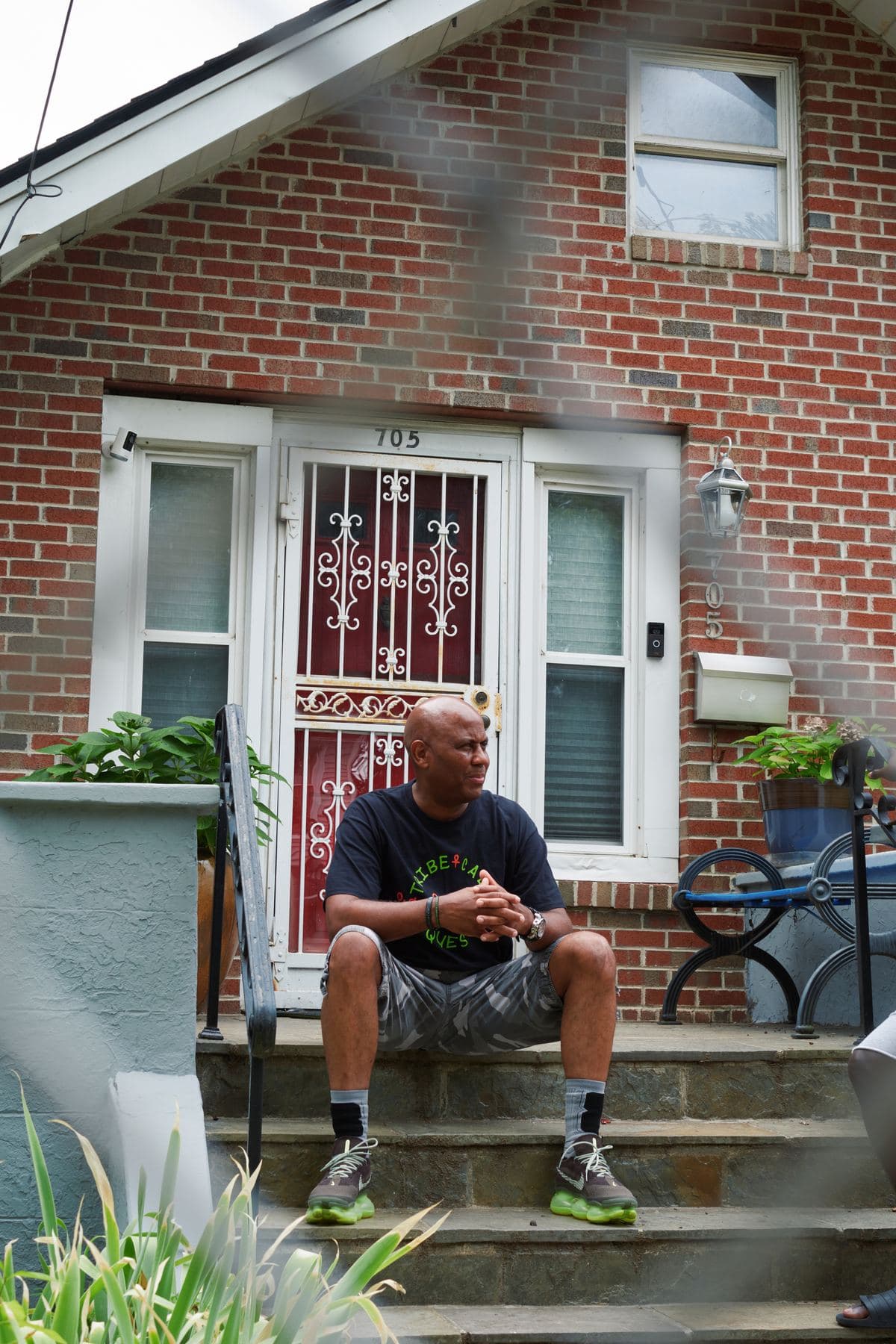 A man sitting on the front steps of a brick rowhouse